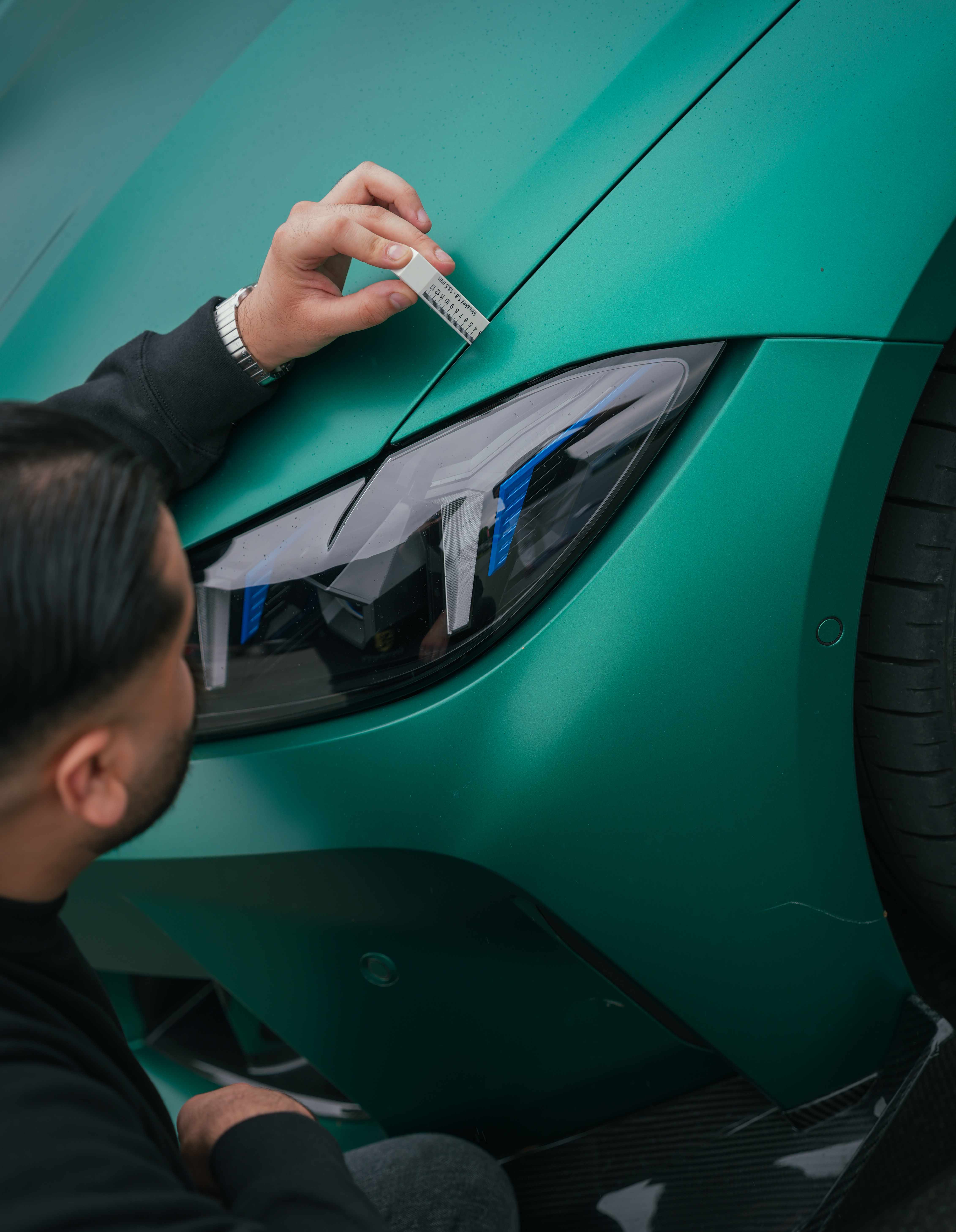 Prüfung des Spaltmaßes zwischen Motorhaube und Kotflügel mit einem Messkeil